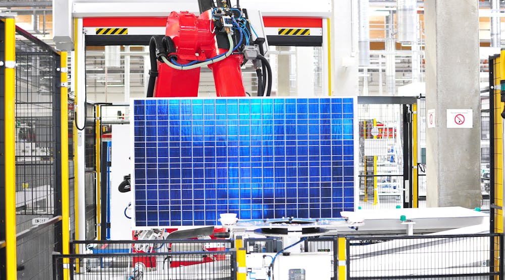 Solar cell clamped in mechanical red arm during manufacturing process.
